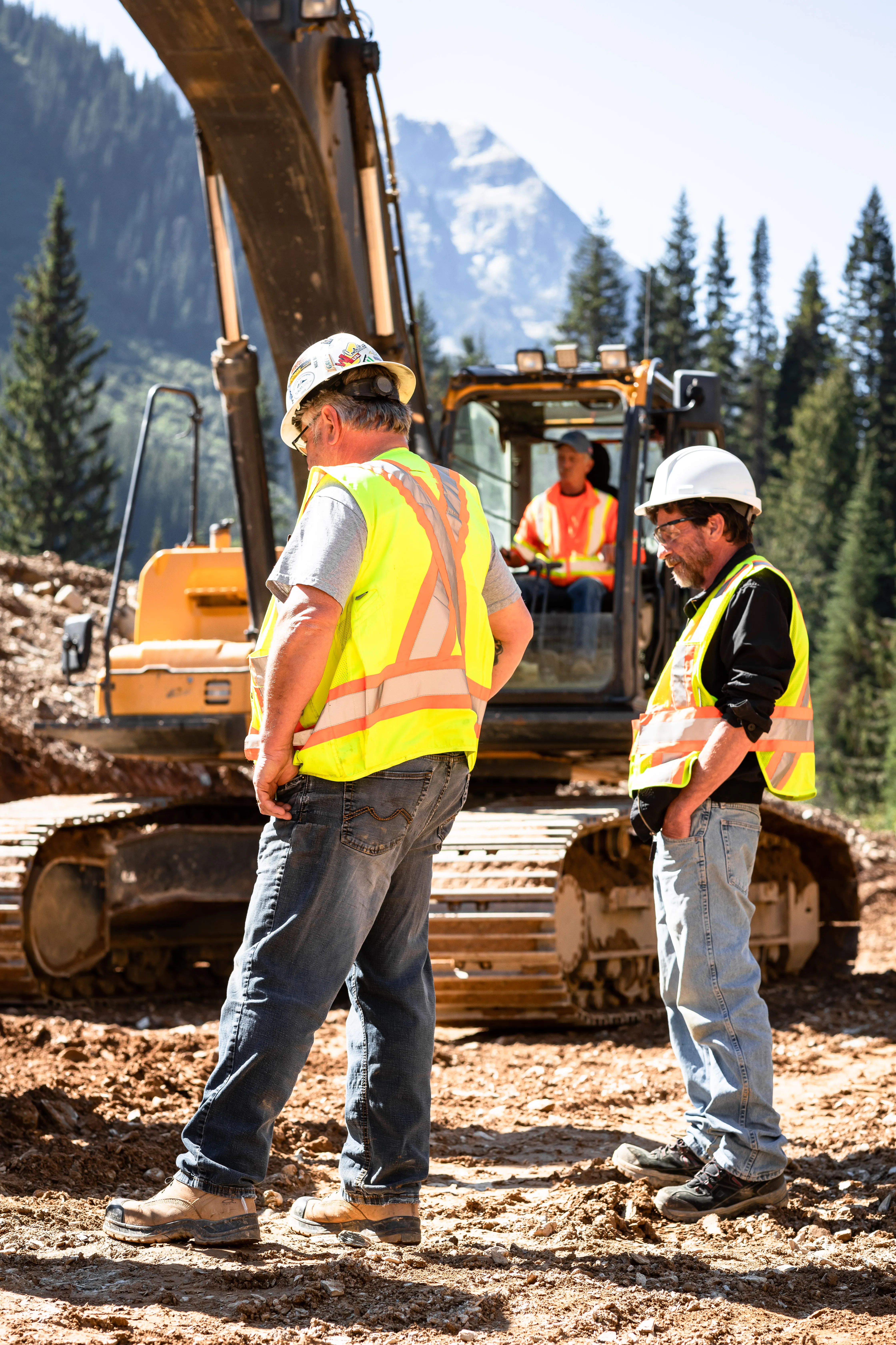 Three Mackay crew members talking with an operator at an excavator
